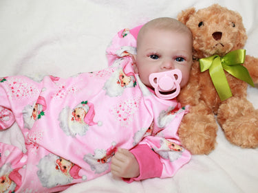 A baby doll with a pacifier rests on a soft bed, showcasing its delicate features and cozy surroundings.